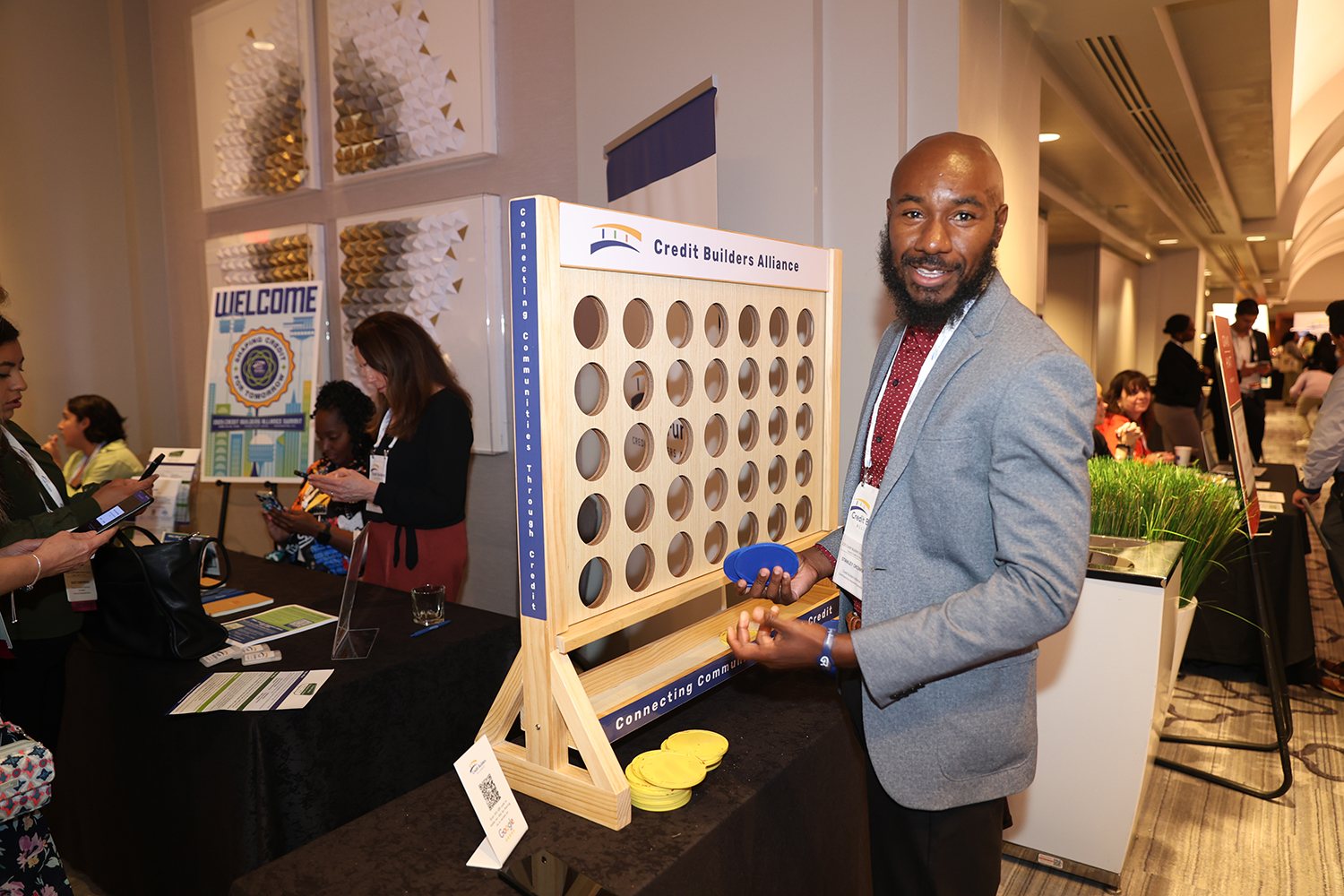 A CBA Summit participant beside a Credit Builders Alliance community activity.