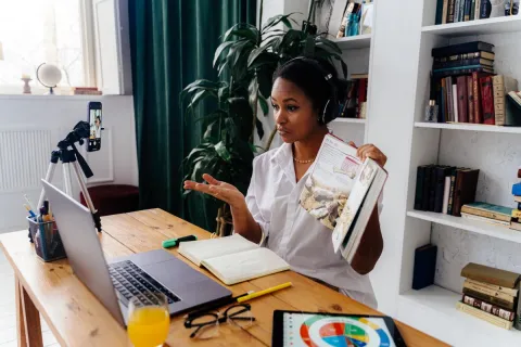 An instructor wearing headphones and presenting learning materials beside a laptop.